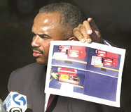At a press briefing on September 12, 2001, FBI Assistant Special Agent in Charge Roland Corvington holds up a photo of the black boxes they hope to recover at the Flight 93 crash site.  “The search will be painstaking,” Corvington said.  “The value of the black box and the information therein cannot be overstated.  Until we recover that, we won’t be able to answer any of the questions you’re asking.”  (“Painstaking search begins in Shanksville,” Mike Faher, Johnstown Tribune-Democrat, September 13, 2001)
